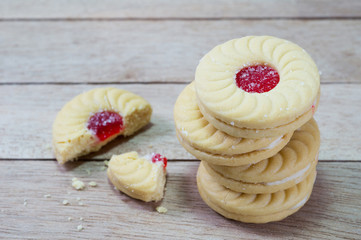 Sweet cookies with cream and jam on wood background