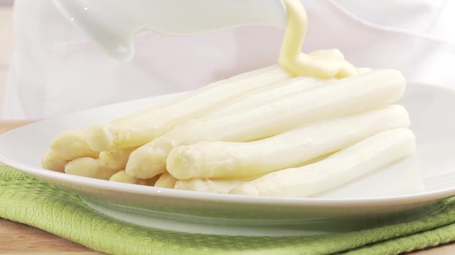 Asparagus with sauce Hollandaise being arranged on a plate