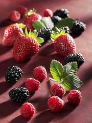 Strawberries, blackberries and raspberries on red background