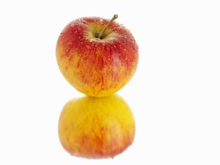 A freshly washed red apple and its reflection