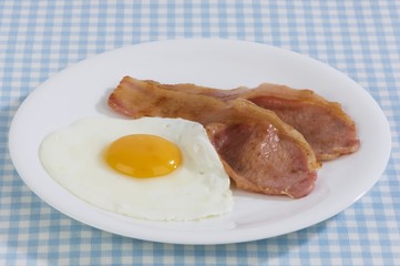 Bacon and egg on a plate, checked tablecloth