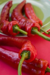 Red chillies on and in front of a green plate