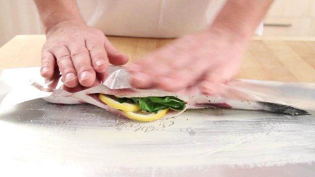 Stuffed bass being wrapped in aluminium foil