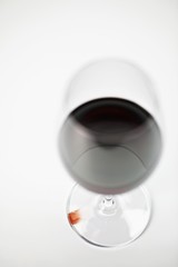 A glass of red wine and a drop of wine on the base of the glass