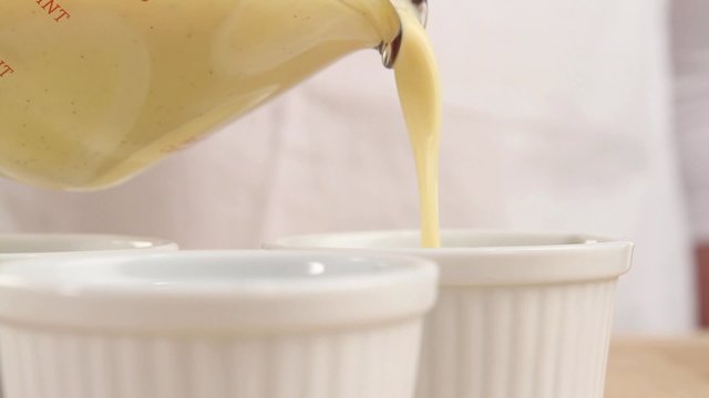 Creme caramel being pour into ramekins