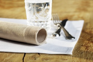 A place setting with a napkin, cutlery and a glass of water