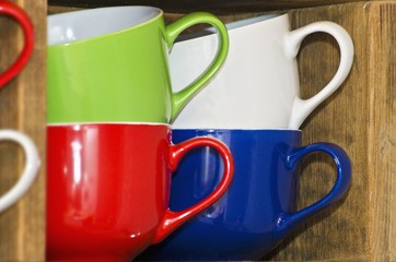 Assorted colours of mugs in a shelf compartment
