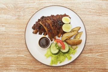 Spare ribs with potato wedges, barbecue sauce and a side salad
