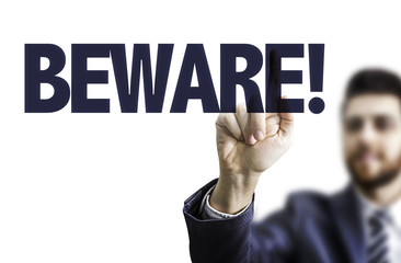 Business man pointing the text: Beware!