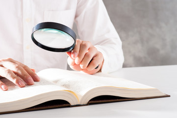 虫眼鏡を使って本を調べる男性