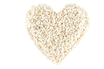 Heart shape made of sesame seeds with no shell viewed from above, isolated on white background.