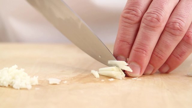 A garlic clove being finely chopped