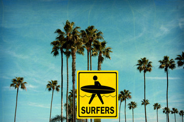 aged and worn vintage photo of surfers sign on beach with palm trees