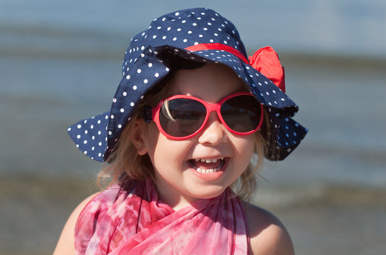 Portrait of happy baby girl in hat and sunglasses