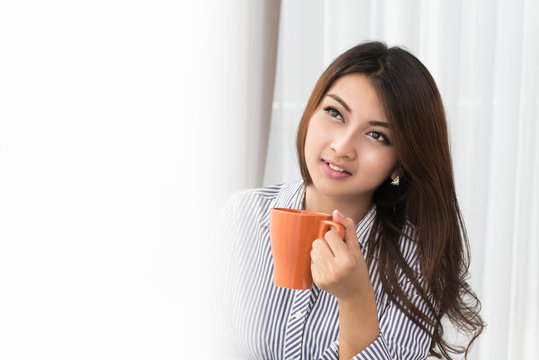 Beautiful asian woman drinking coffee at home