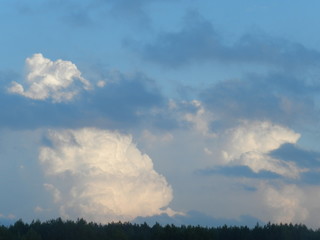 Белые облака над полем на сине-голубом летнем небе