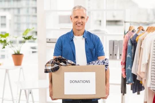 Smiling casual businessman holding donation box