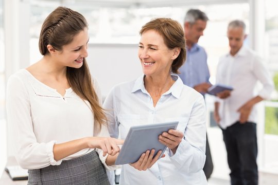 Smiling businesswomen using tablet in a meeting