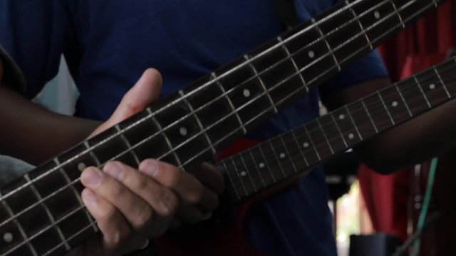 closeup hand of man playing electrical guitar bass