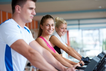 friends  exercising on a treadmill at the bright modern gym