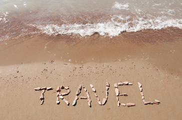 travel written on sandy beach near sea