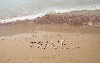 travel written on sandy beach near sea