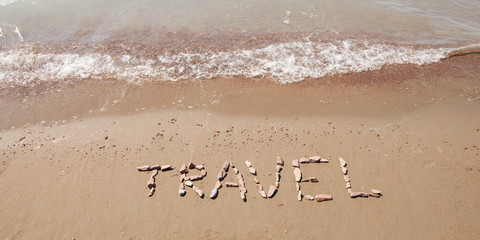 travel written on sandy beach near sea