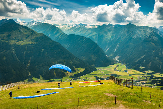 starting and waiting paragliders in mountains with peaks view