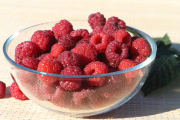 Basket with fresh ripe raspberries standing on a table in a garden
