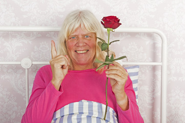 Cheerfull woman in bed with rose - 89518529