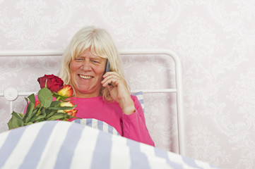 Happy woman in bed with roses and telephone - 89518541