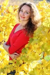 Beautiful young curly girl in yellow grape vineyard, autumn time