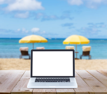 laptop computer on wood table with blur beach background © littlestocker