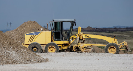 Grader leveling gravel on road construction site