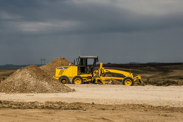 Obraz premium Grader leveling gravel on road construction site
