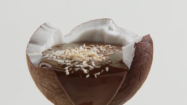 Half a coconut with chocolate sauce and grated coconut