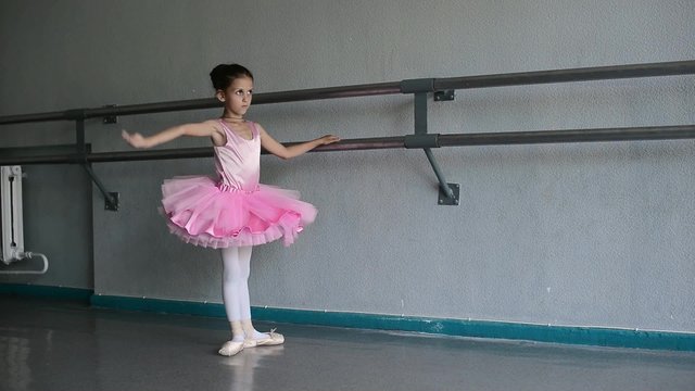  little ballerina puts on pointes  in the ballet hall