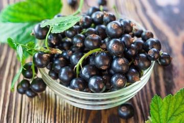 Black currants in bowl on wooden table