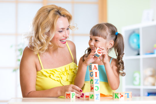 Smiling mother assisting girl in playing block game
