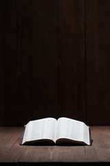 Image of a Holy Bible on wooden background in a dark space © 4Max