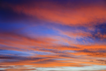 Obraz premium Fiery September evening skyscape with clouds lit by red sunset against a dark blue sky. UK Britain