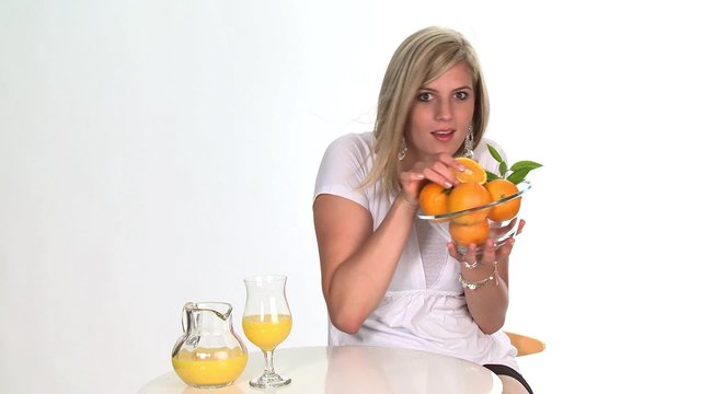 Blond woman holding a glass bowl of oranges