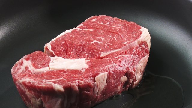 Frying rib eye steak in a frying pan