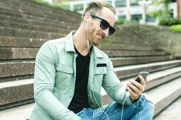Obraz premium Man listening to the music with earbuds from a smart phone 
