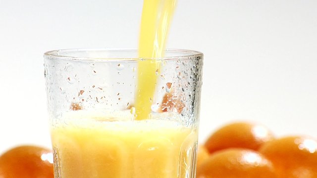 Pouring orange juice into a chilled glass (close-up)