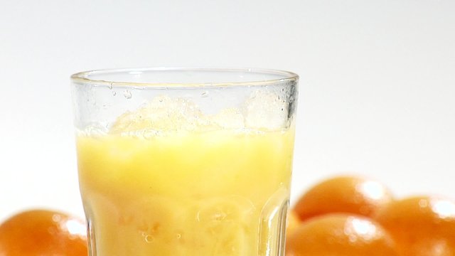 Pouring orange juice into a glass of crushed ice (close-up)