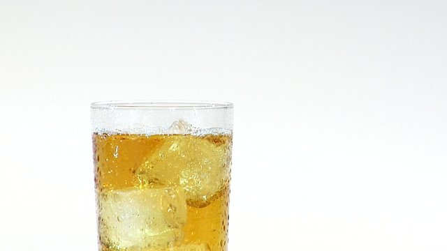 Pouring apple juice from a jug into a glass of ice cubes