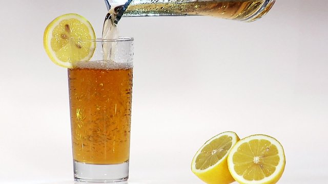 Pouring apple juice into a glass with a slice of lemon