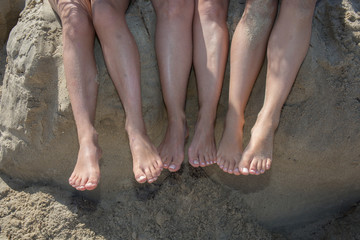 Legs of several girls lying on sandy beach