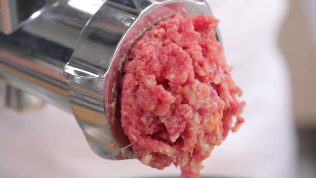 Putting minced meat and vegetable mixture through mincer